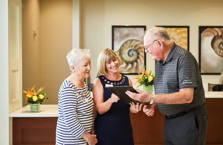 A concierge helps two older adults.