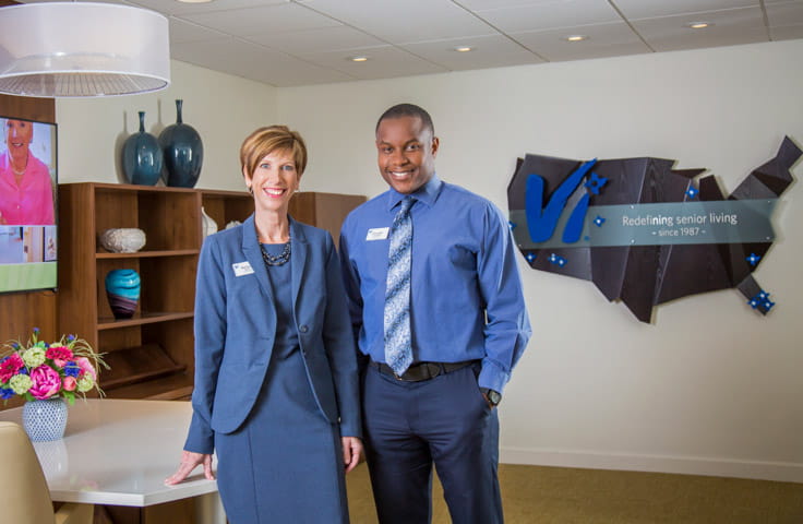 Two members of Vi at Lakeside Village's staff smile in the sales center.
