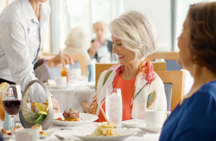 A woman smiles while she is served her meal.