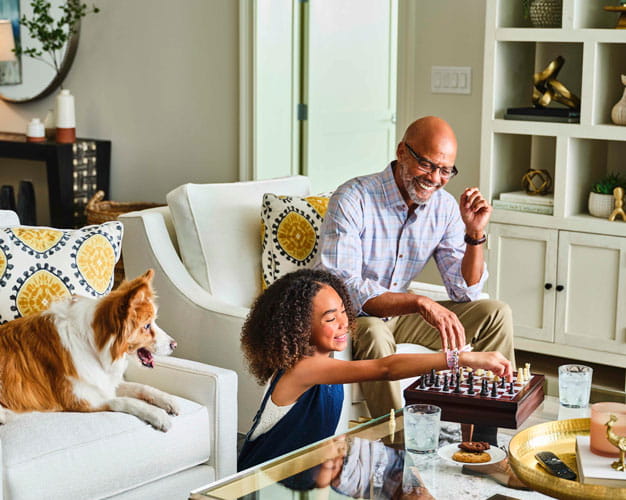 A grandfather plays chess with his granddaughter.