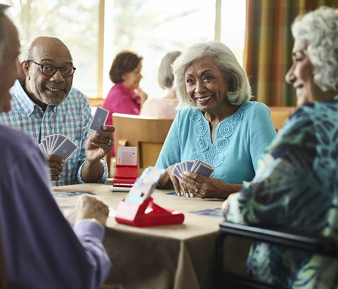 Four people playing cards and smiling at Vi at Aventura