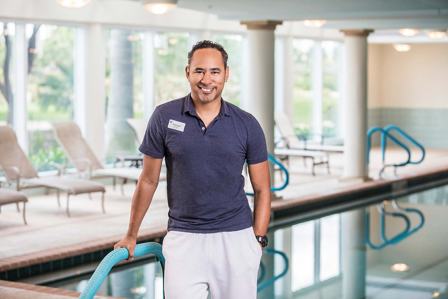 A Vi at Aventura staff member smiling and standing in front of the indoor pool