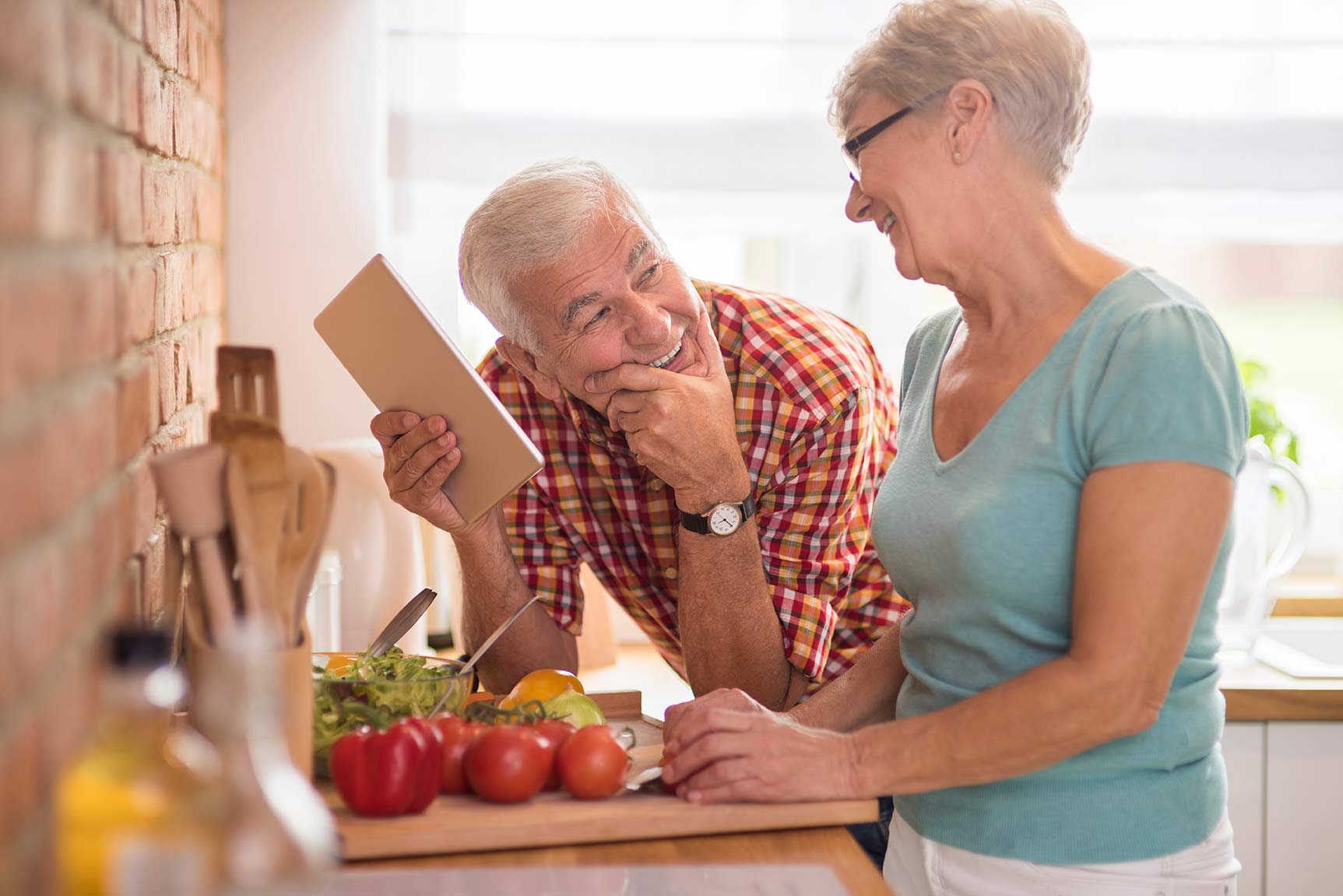 A couple laughing in the kitchen while preparing food