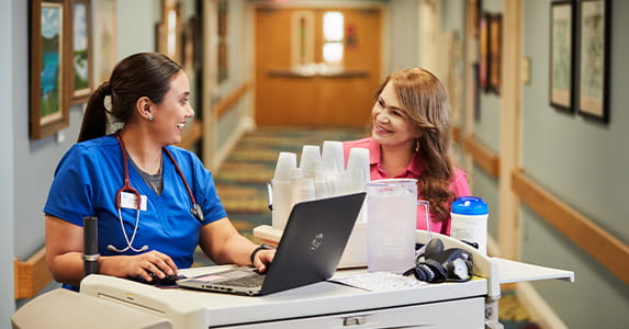 Two woman nurses chatting at their cart. 