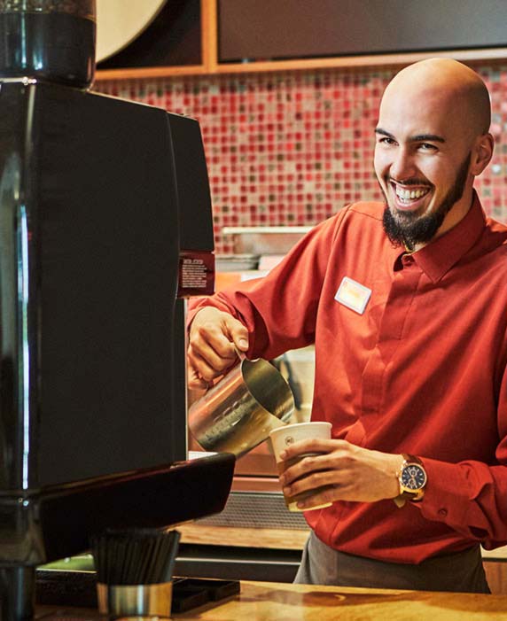 A Vi at Bentley Village staff member pours a drink at the cafe