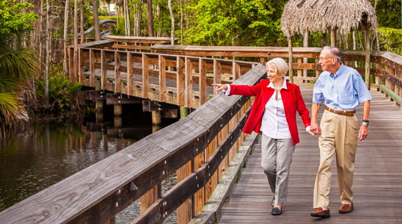 A couple walks on a boardwalk at Vi at Bentley Village.