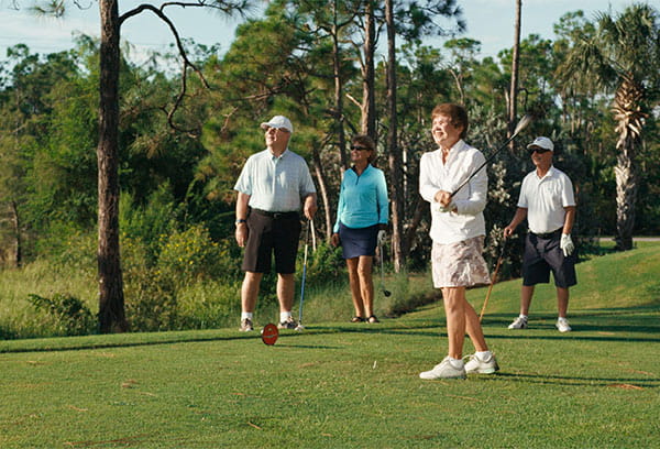 A women swinging a golf club with friends.