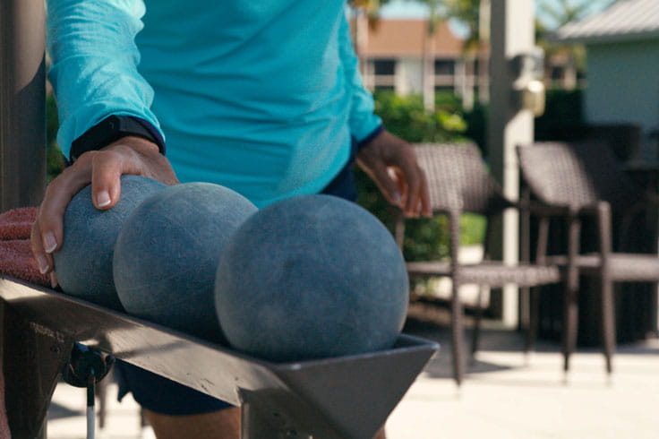 A close-up photo of a hand reaching for a bocce ball