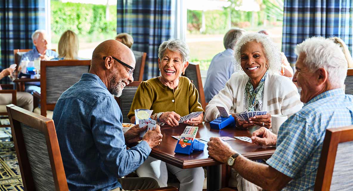 A group of people playing cards and laughing. 
