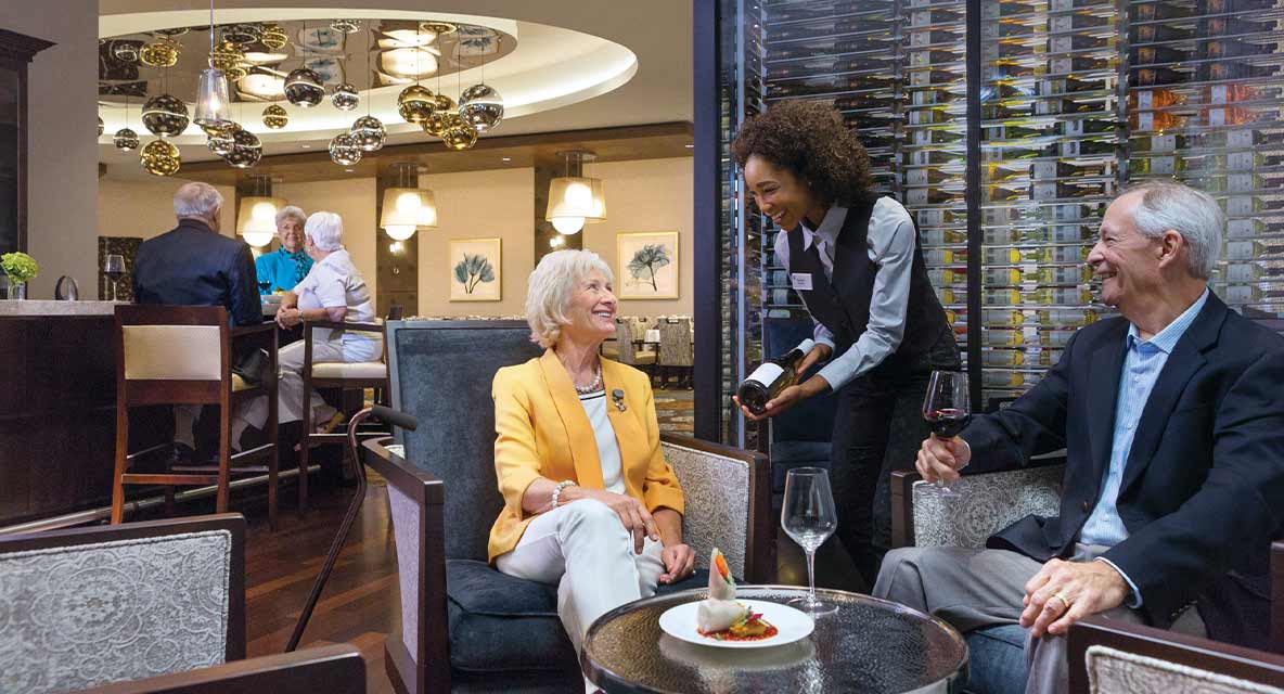 Two people getting served a bottle of wine. 