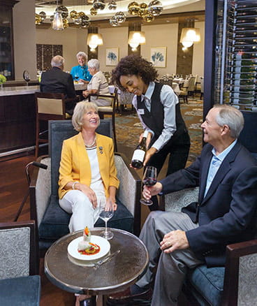 A staff member shows a bottle of wine to residents.