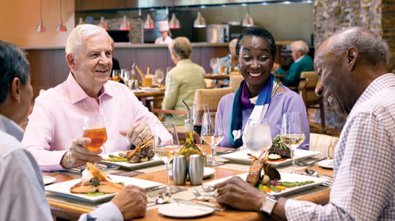 Four people sit around laughing over a meal.