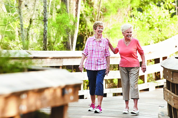 Two women walking on path outside. 