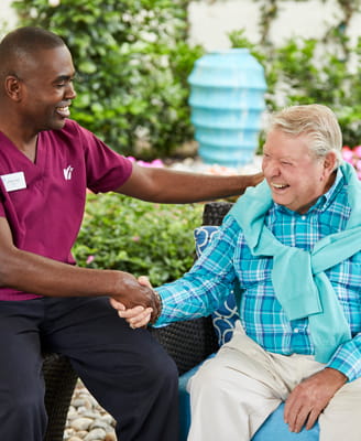A resident smiles with a member of care staff.