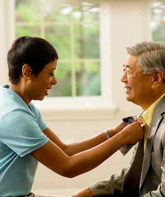 A woman ties a senior's tie.