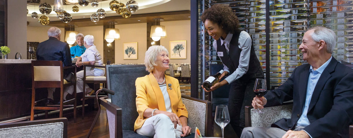 A server presents a bottle of wine to a couple in the Azure dining room.