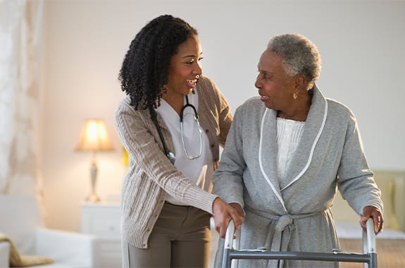 A nurse helping a women with a walker.