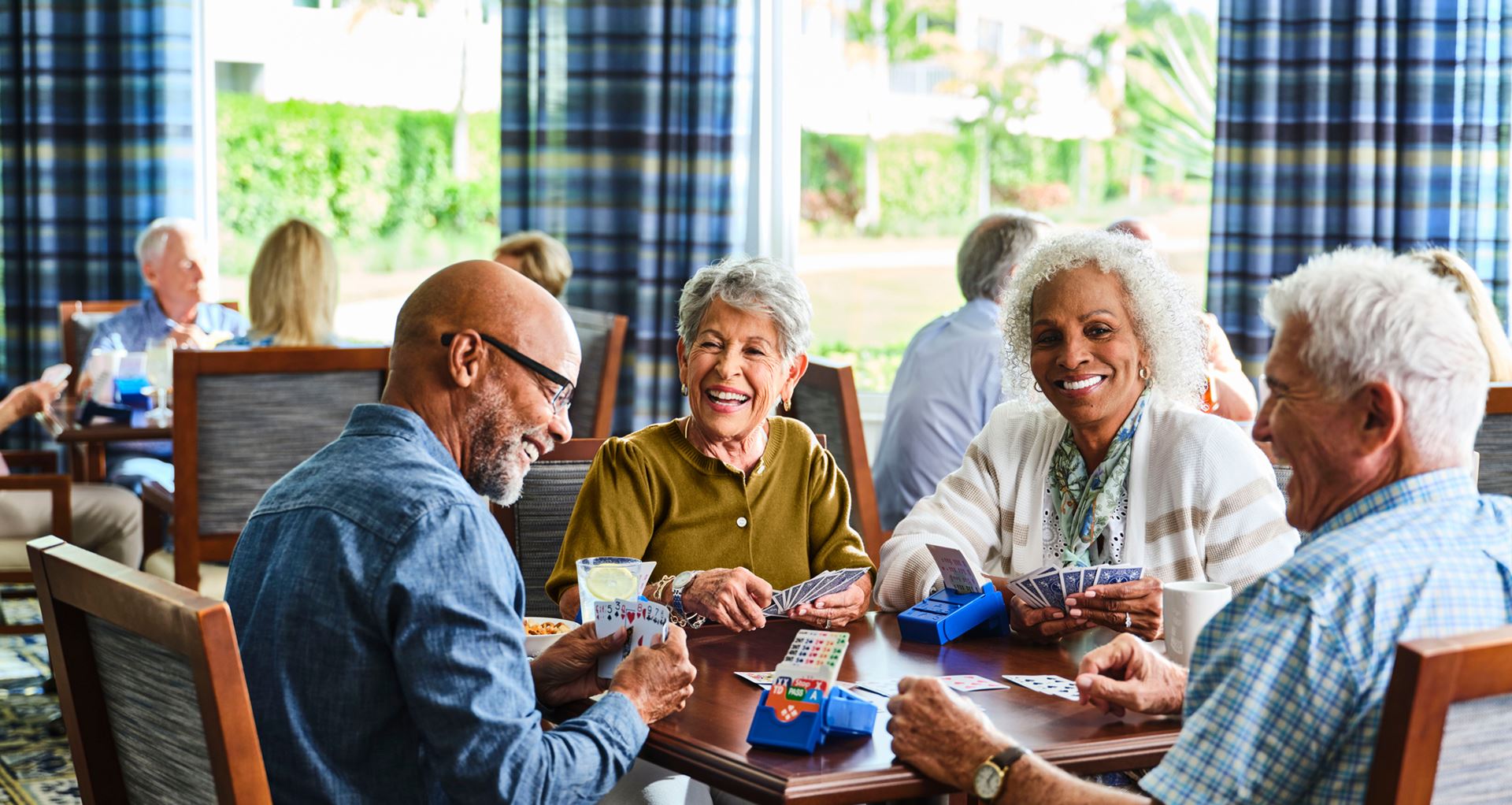 Four friends laugh over a game of bridge.
