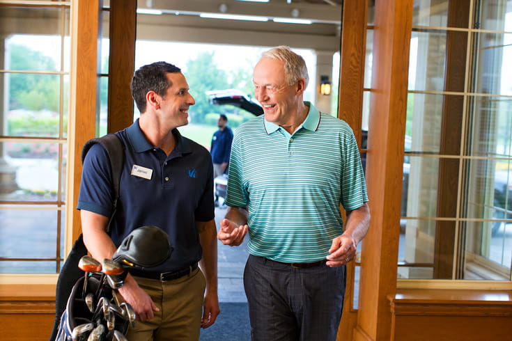 A man and a golf instructor walk through the doors.