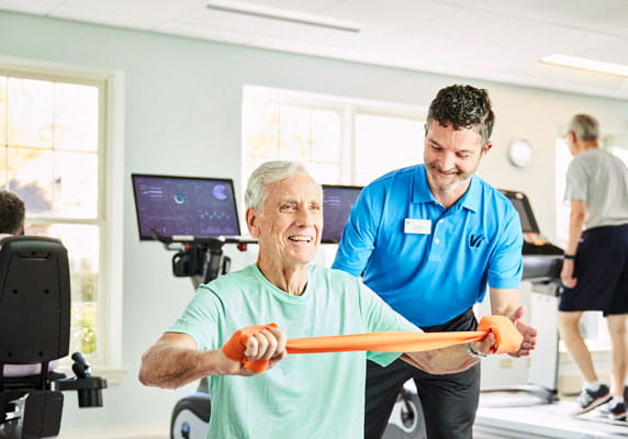 The fitness coordinator helps a resident work out.