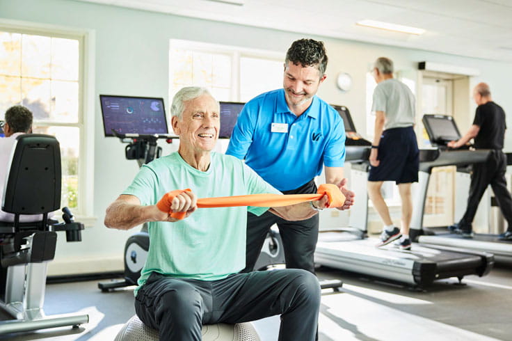 A man works with an instructor at the gym.