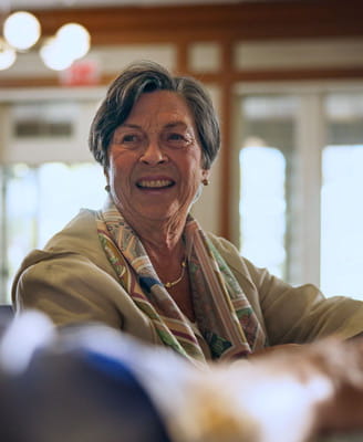 A resident smiles while enjoying a glass of wine at Vi at The Glen's bar.