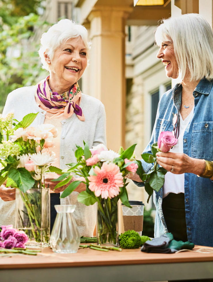 Two women arranging flowers together.