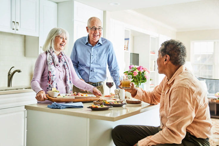 Two men and a woman gather in a kitchen.