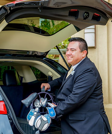 A Vi employee unloads golf clubs from a trunk