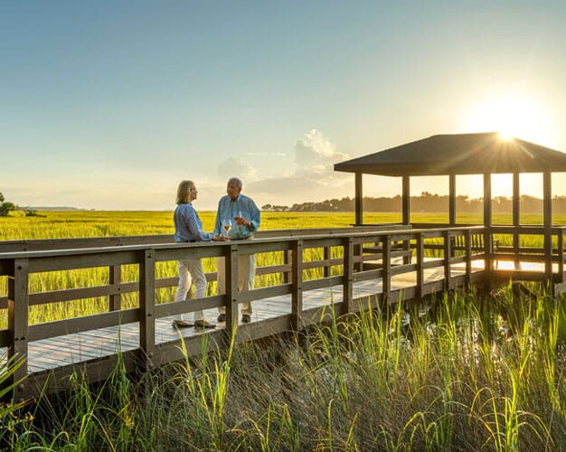 A couple talks together on the boardwalk at sunset.