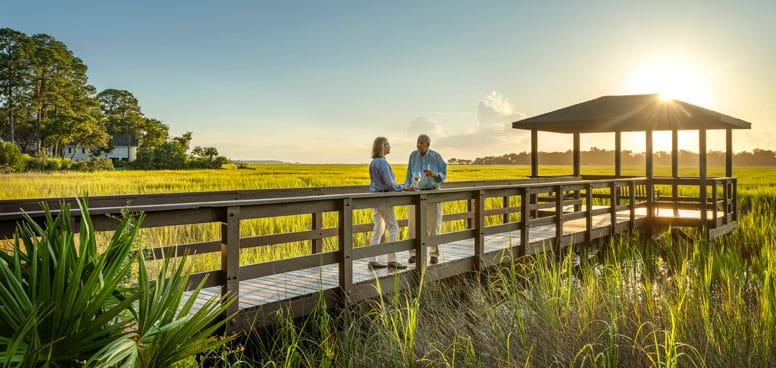 Two people stand at the TidePointe gazebo at sunset.
