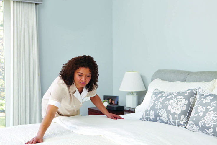 A housekeeping team member smooths bedding.
