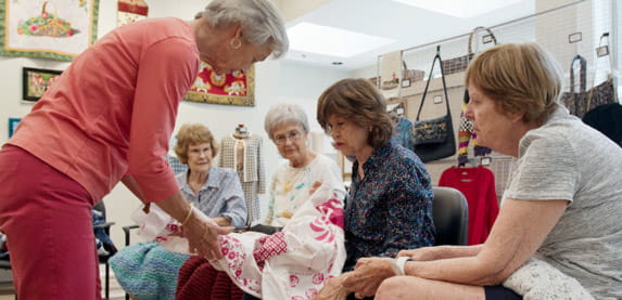 Darn Yarn group members examine a cloth together.