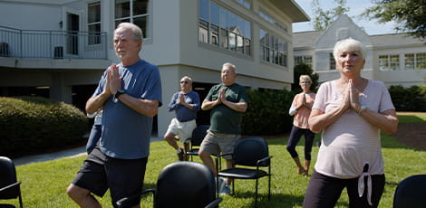 Residents doing chair yoga outside.