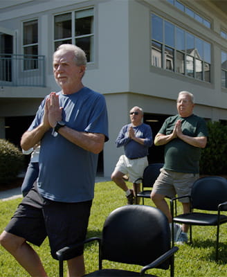 Residents doing chair yoga outside.