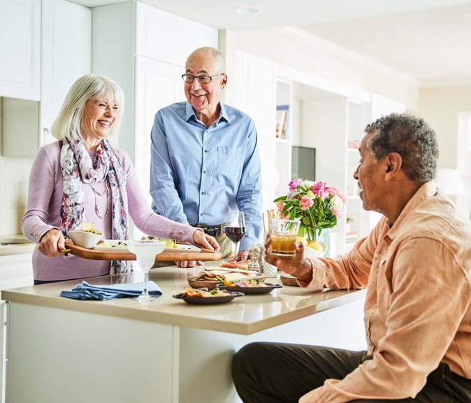 Three people enjoy cocktails in a home.