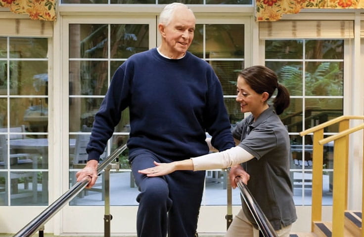 A healthcare worker does exercises with an older man.