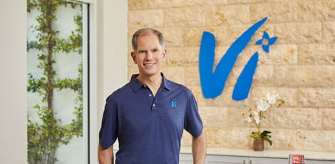 Gary Smith stands in front of a wall featuring the Vi logo.
