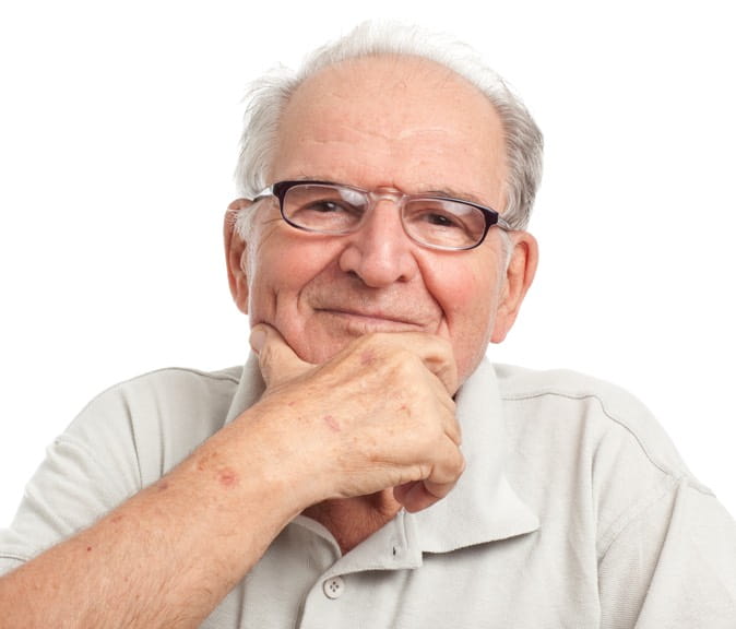 A man in glasses smiles while resting his chin in his hand.