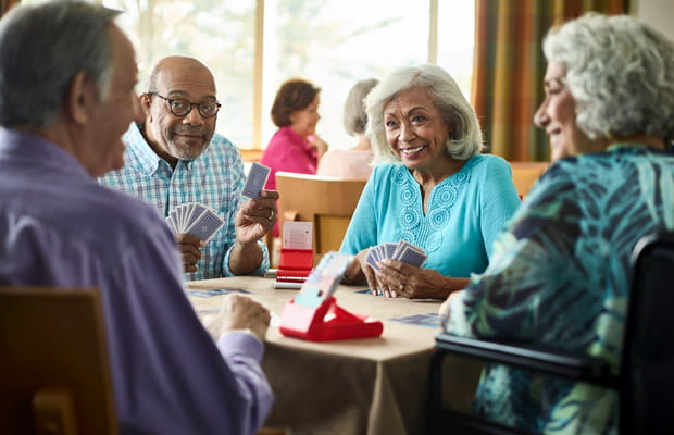 Four people sit together at a bridge table.