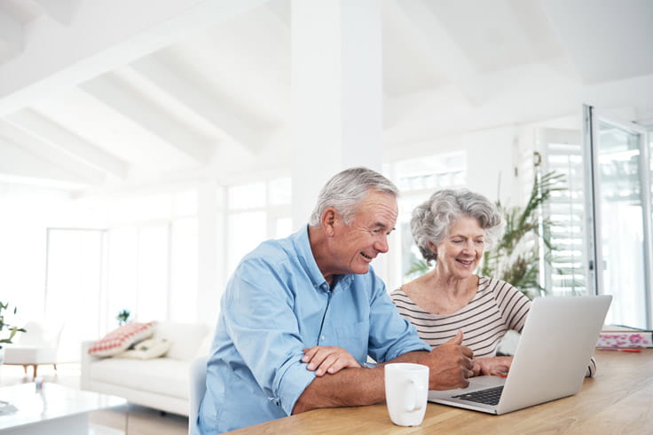 A couple looks together at a laptop screen.