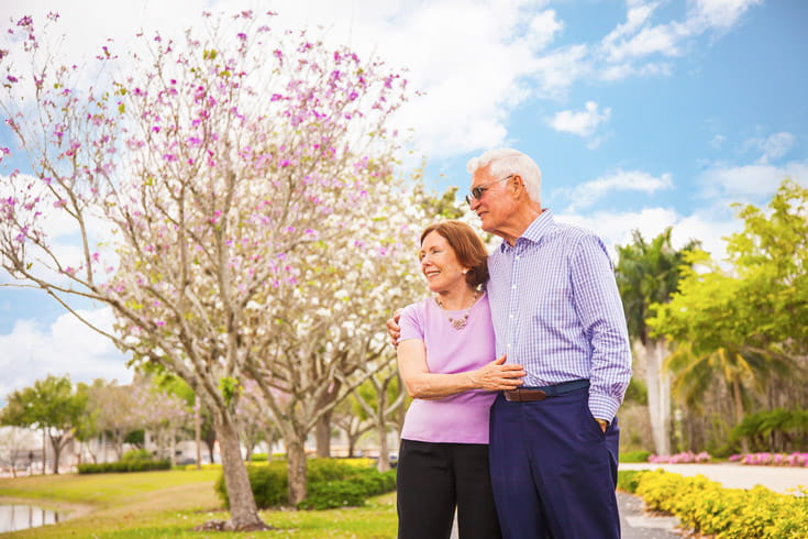 A man and woman lock arms and look into the distance.