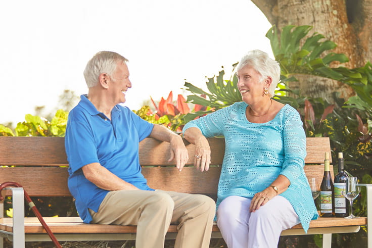 A man and woman sit on a bench and chat.