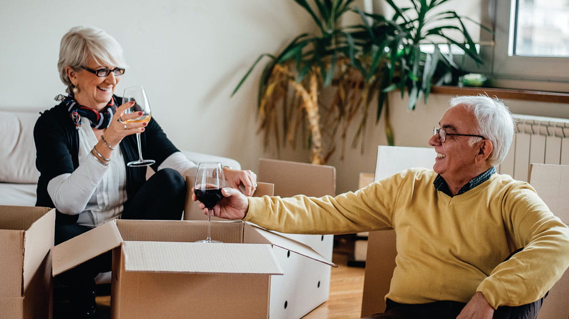 Man and woman drinking wine while packing 