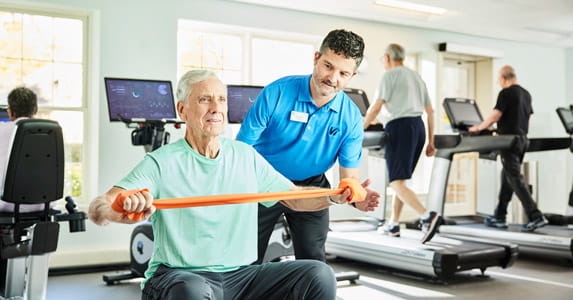 An employee works in a gym with a resident.