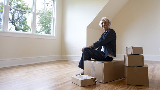 A woman sits on a small pile of moving boxes.