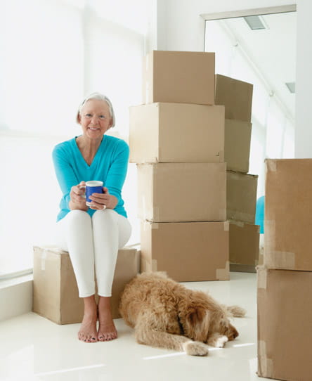 A woman sits among moving boxes.