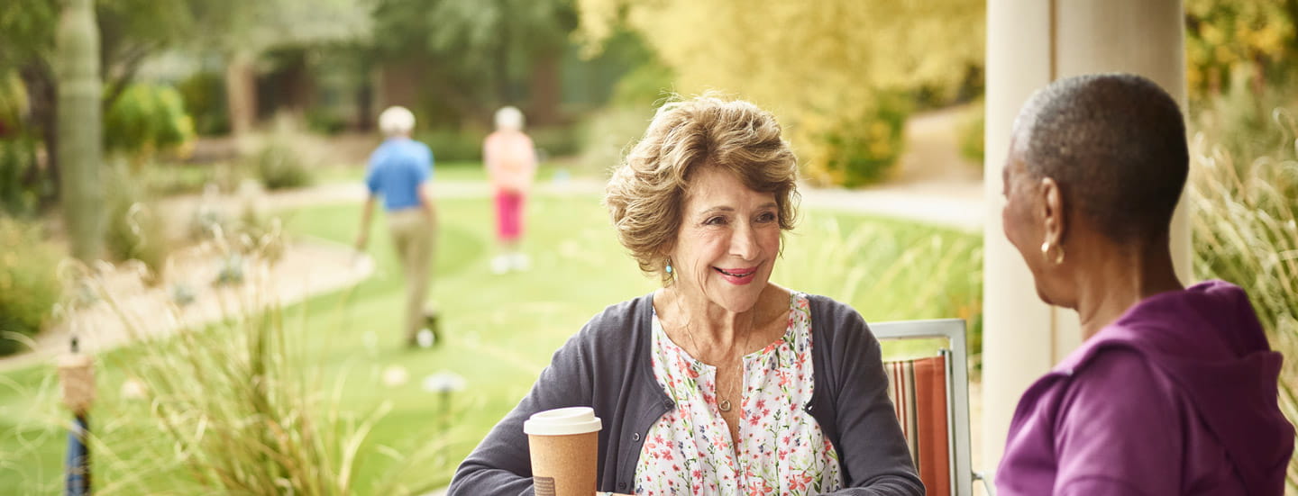 Two women chat while sitting outside.