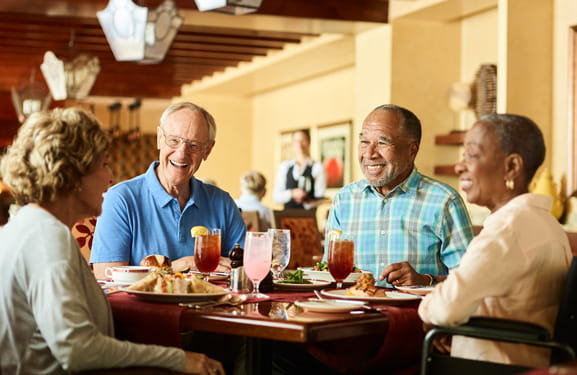 Two couples laugh over a meal together.