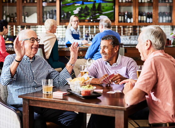 A group of men sit around a card table and laugh.